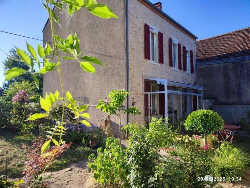a brick building with a door and some plants at Au Jardin de Curé in Auxonne