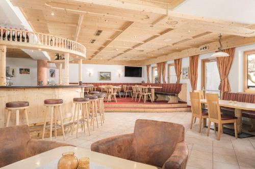 a large room with a bar and tables and chairs at Alpenhotel Tirolerhof Gerlos in Gerlos
