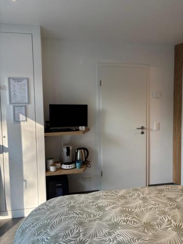 a bedroom with a bed and a door with a television at La Halte in Malmedy