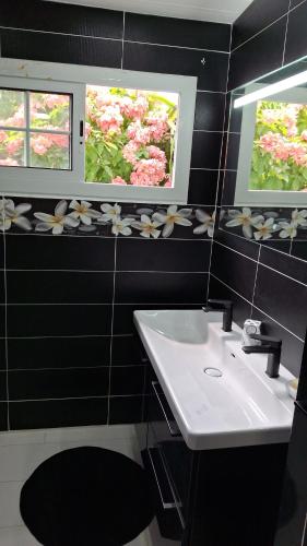 a bathroom with a sink and two windows with flowers on the wall at l'océan bleu in Le Moule