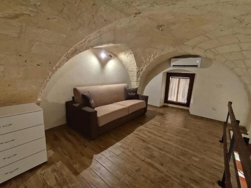 a living room with a couch in a stone wall at Casa vacanze LU FUMARU in Nardò