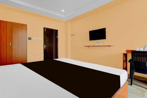 a bedroom with a bed and a tv on the wall at Collection O Bheemili Beach Visakhapatnam in Visakhapatnam
