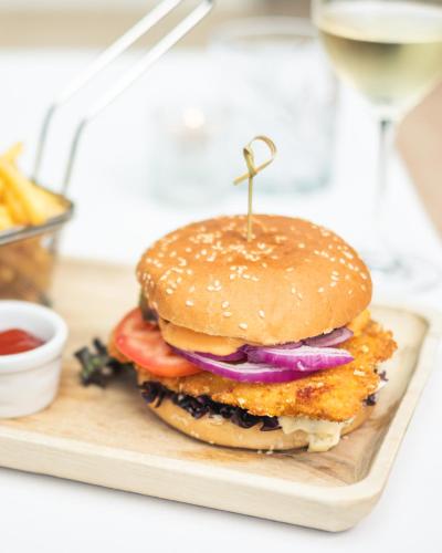 a hamburger on a plate with a glass of wine at Alpenhotel Tirolerhof Gerlos in Gerlos