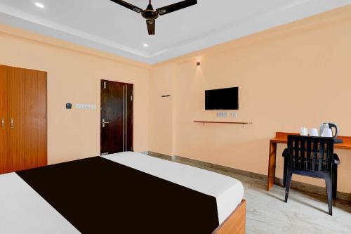 a bedroom with a bed and a desk with a television at Collection O Bheemili Beach Visakhapatnam in Visakhapatnam