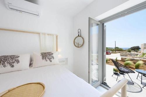 a white bedroom with a large bed and a balcony at Fos Residence Dryos in Drios