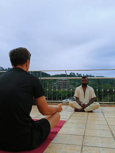 two men sitting on the floor on a roof at Green Peak - Mountain View Hotel & Restaurant in Ella