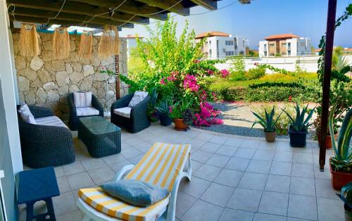 a patio with chairs and plants and a stone wall at Boho Beach Apartment in Tatlisu