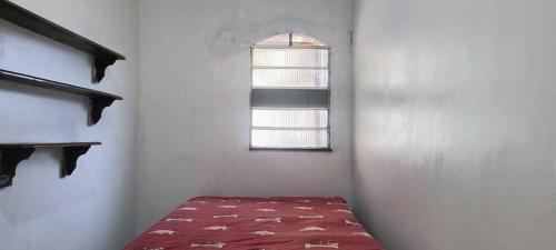 Habitación con cama roja y ventana en Casa da Família Nascimento, en Ananindeua