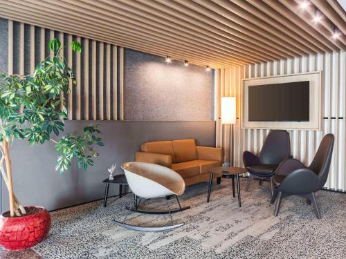 a living room with a couch and chairs and a tv at B&B HOTEL Gotha-Hbf in Gotha