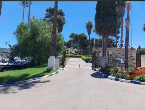 a driveway with palm trees and a gate in a park at Armonia buglaow residence MARSA MDIQ in M'diq
