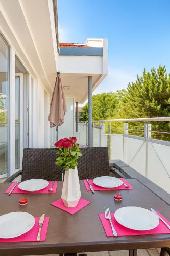 a table with pink napkins and a vase with red roses at ZingstUrlauber in Zingst