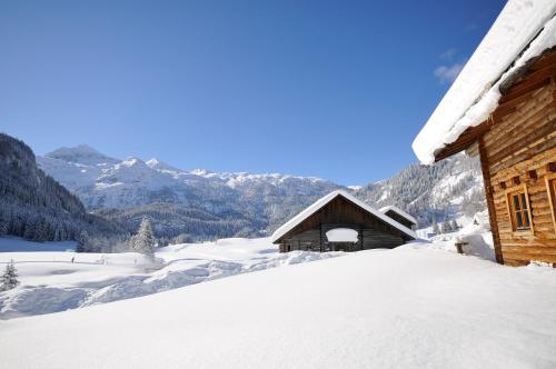 a snow covered cabin with mountains in the background at Hotel Zehnerkar & Hotel Obertauern in Obertauern