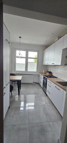 une cuisine avec des armoires blanches et une table à l'intérieur dans l'établissement Apartament 2 pokojowy z widokiem na morze, à Sarbinowo