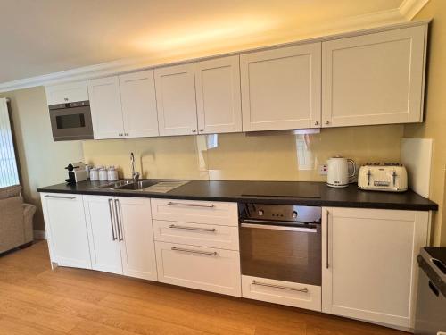 a kitchen with white cabinets and a black counter top at Allt Nan Ros Apartments fort william in Onich