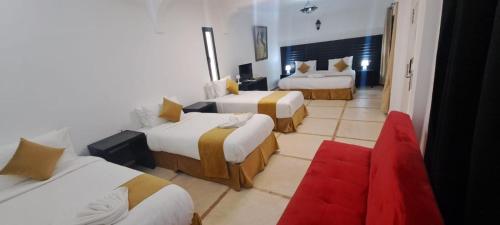 a hotel room with two beds and a red carpet at Hôtel Calipau Riad Maison d'Hôtes in Dakhla