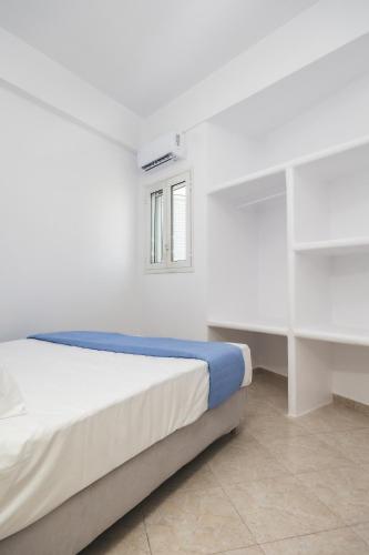 a white bedroom with a bed and a window at Alkara Square in Naxos Chora