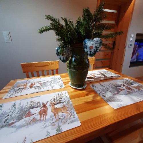 a wooden table with pictures of deer and a plant at Domek pod Skiełkiem in Łukowica