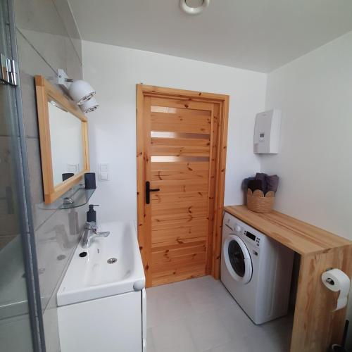a bathroom with a washing machine and a wooden door at Domek pod Skiełkiem in Łukowica