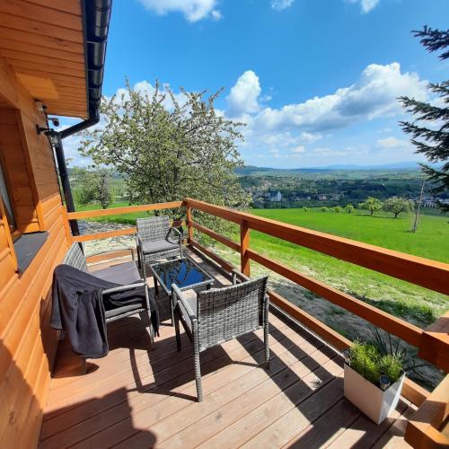 a deck with two chairs and a table with a view at Domek pod Skiełkiem in Łukowica