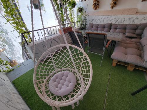 a white rattan chair sitting on a patio withgrass at House with sauna and fireplace in Ardales