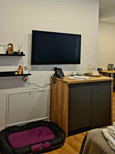 a living room with a tv on a wooden stand with a desk at Hotel Maslina in Seget