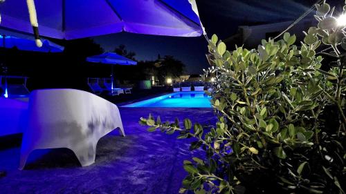 a swimming pool at night with a table and an umbrella at Villa Malvasio Pool and Jacuzzi Room Sassari in Sassari