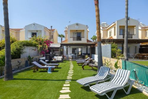 a yard with lounge chairs and palm trees at Beachfront Villa Carpe Diem in Kiti