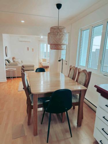 a dining room with a wooden table and chairs at À Bon Port in Perce