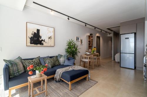 a living room with a blue couch and a kitchen at The Braemar - Cape 8 Collection in Cape Town