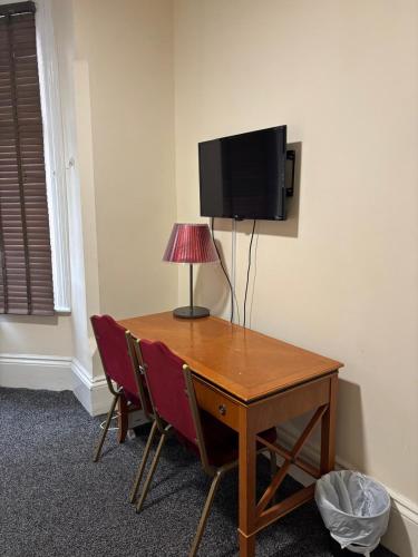 a desk with a lamp and a television on a wall at The Tudor House Hotel in Nottingham