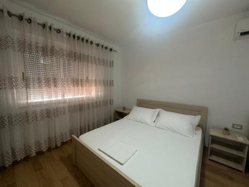 a bedroom with a white bed and a window at Lenci's Apartment in Berat