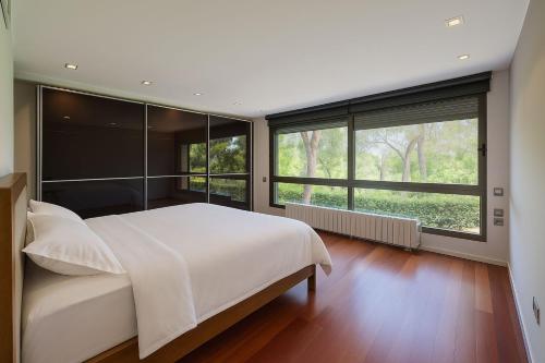 a bedroom with a large white bed and large windows at Imperiale Golf House in Bétera