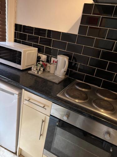 a kitchen with a stove and a microwave at The Tudor House Hotel in Nottingham