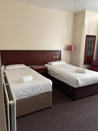 a hotel room with two beds and a lamp at The Tudor House Hotel in Nottingham