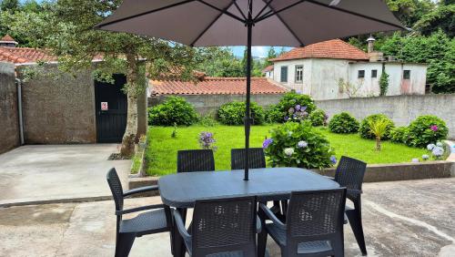 Una mesa y sillas con una sombrilla en un patio. en Chalé da Serra, en Santo da Serra