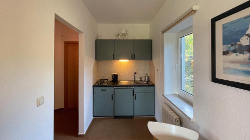 una pequeña cocina con armarios azules y una ventana en Fewo Mohnrot - Fulgenhaus, en Klein Bollhagen
