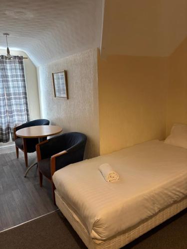 a hotel room with a bed and a table and chairs at The Tudor House Hotel in Nottingham