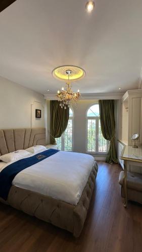 a large bedroom with a large bed and a chandelier at Hotel Ambasada QTA in Patza-Kuqani