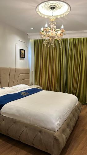 a bedroom with a large bed and a chandelier at Hotel Ambasada QTA in Patza-Kuqani