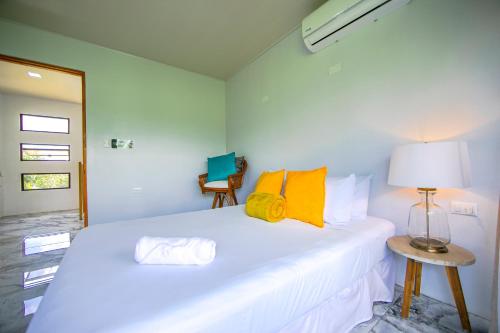 a bedroom with a large white bed with yellow pillows at Villas Sapiens Arenal in Fortuna