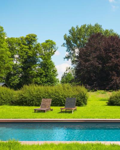 two benches sitting next to a swimming pool at Domaine des Chanoines blancs in Gouy-Saint-André
