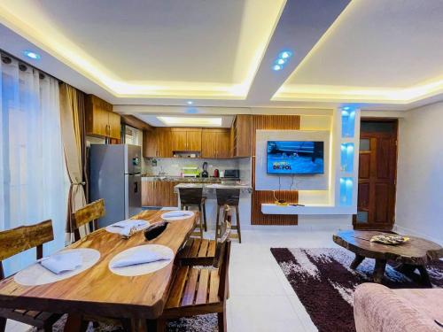 a living room with a wooden table and a kitchen at Luxurious Cozy Apartment in Kampala