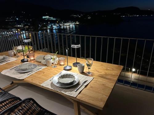 a wooden table with plates and wine glasses on a balcony at Apartment Sunkiss in Almirida