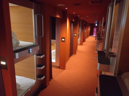 a corridor in a train with many bunk beds at Capsule Inn Osaka (Male Only) in Osaka