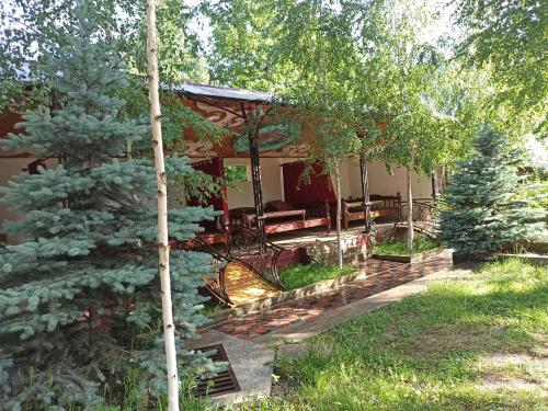 a house with a porch with benches and trees at The Walnut Tree Guest house in Arslanbob