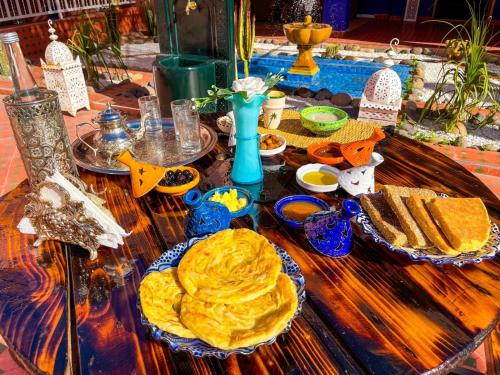a wooden table with plates of food on it at FERME D'HOTES BARGHALi in Marrakech