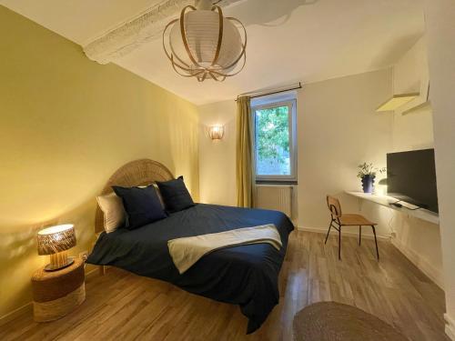 a bedroom with a bed and a window and a television at Suites zen dans maison d'hôtes avec piscine intérieure et jardin in Ventenac-Cabardès