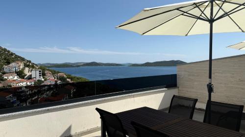 a balcony with an umbrella and a table and chairs at Apartmani Srdarović in Drage