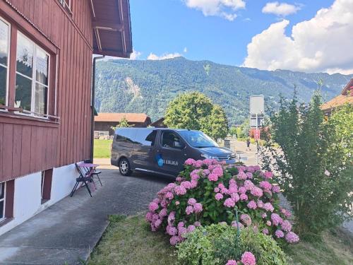 a van parked next to a building with flowers at Interlaken house with Harder Kulm view in Matten