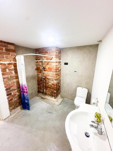 a bathroom with a white sink and a brick wall at Wagner's Refuge 1 in Riga